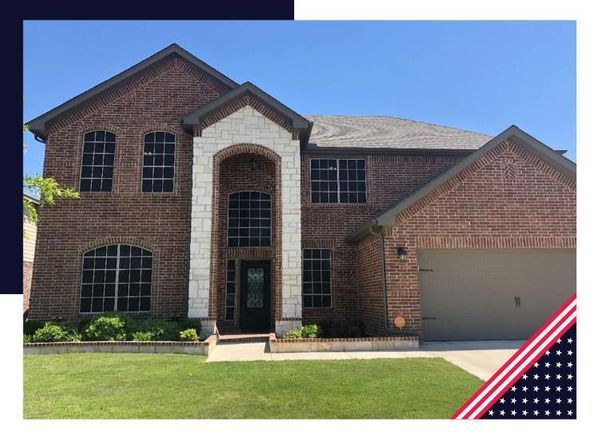Brick two-story house with stone archway over front door and attached garage; green lawn.