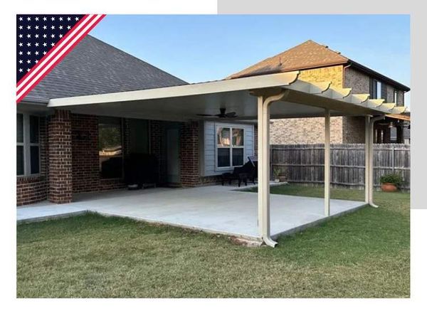 Patio with a covered seating area attached to a brick home with an American flag.
