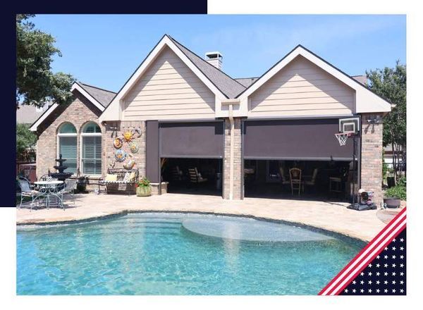 Swimming pool with open garage doors and shades; a basketball hoop is mounted.