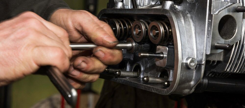 Hands Adjusting a Valve on an Open Engine Cylinder Head — JNL Crankshaft Services in Palmerston City, NT