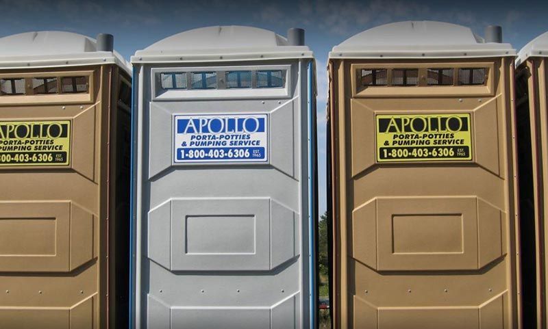 Three portable toilets are lined up next to each other.
