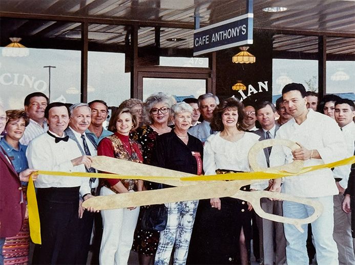 Group of people cutting a yellow ribbon at the grand opening of Cafe Anthony's Italian restaurant.