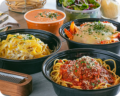 Several pasta dishes in black containers, with soup, and salad.