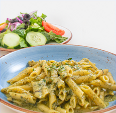 Pasta with pesto sauce in a blue bowl, served with a side salad.