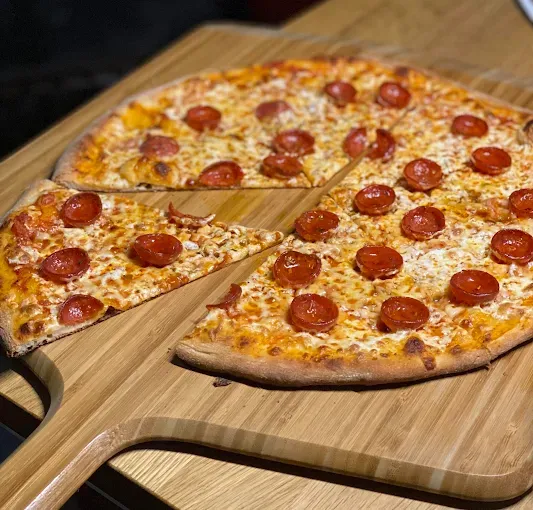 Pepperoni pizza on a wooden cutting board, with one slice removed