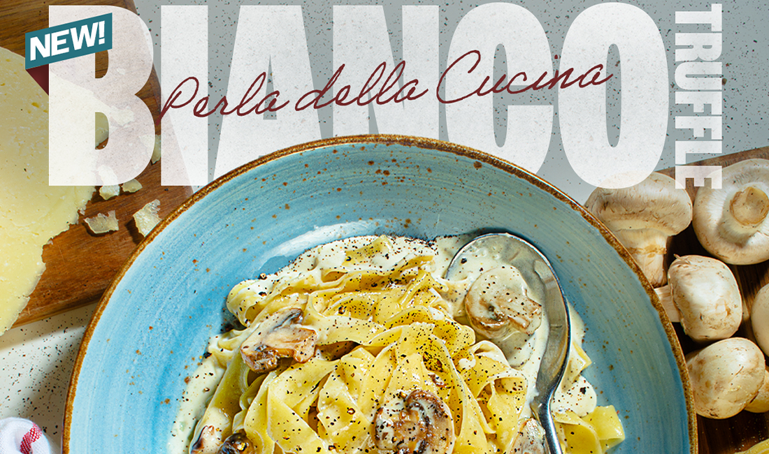 Pasta dish with creamy sauce, mushrooms, and truffle, served in blue bowl.