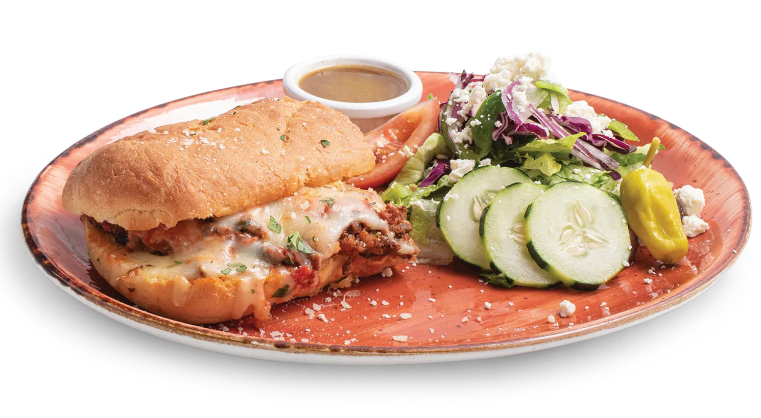 A toasted sub sandwich with melted cheese next to a side salad with cucumbers, feta, and a small cup of dressing.