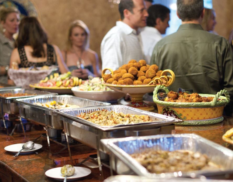 Buffet table with various dishes; people in background.