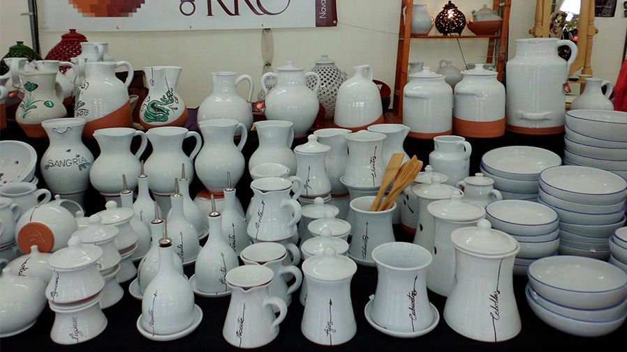 Una mesa llena de jarrones y cuencos blancos.