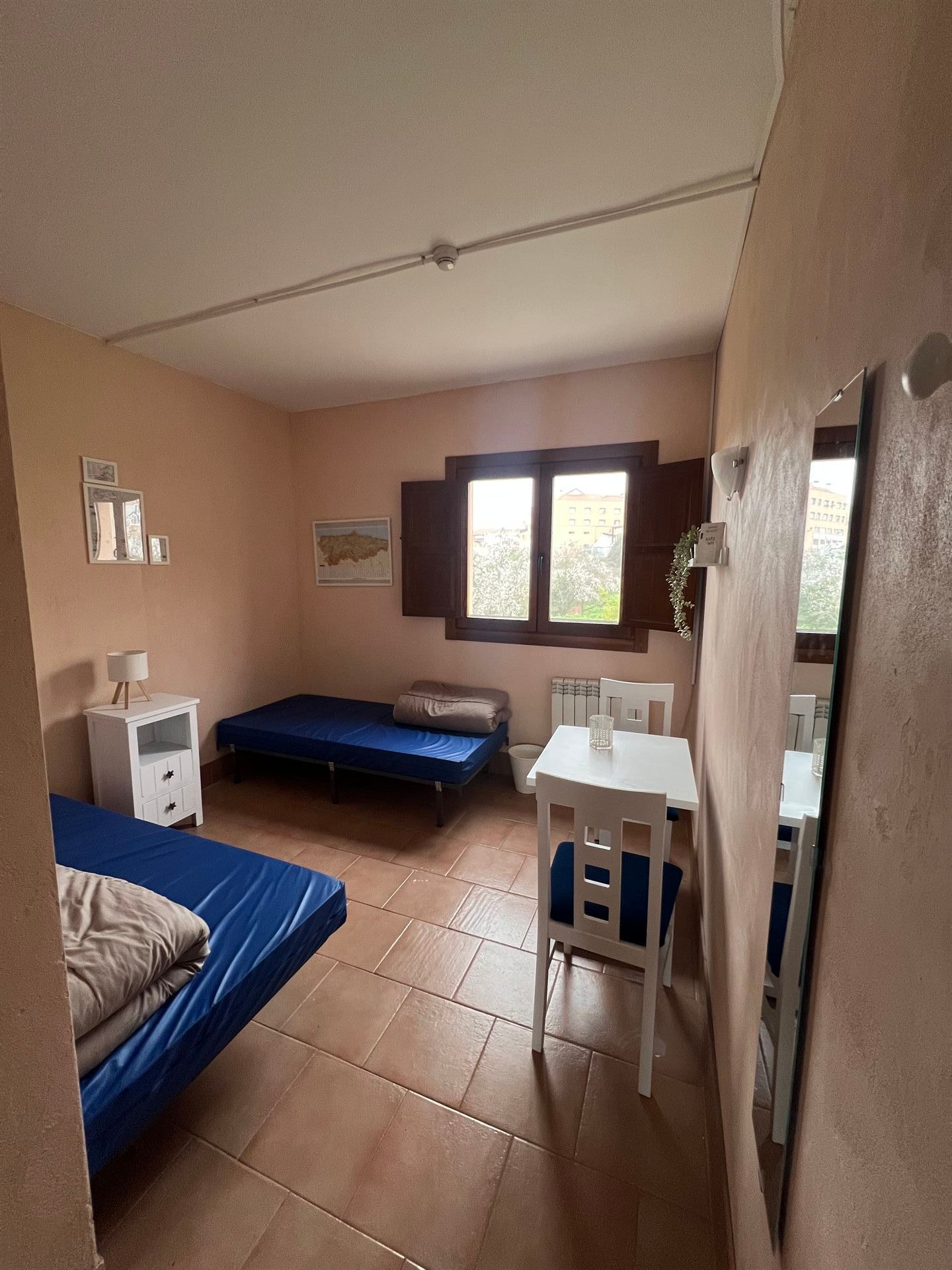 Un dormitorio con dos camas, una mesa y un espejo.