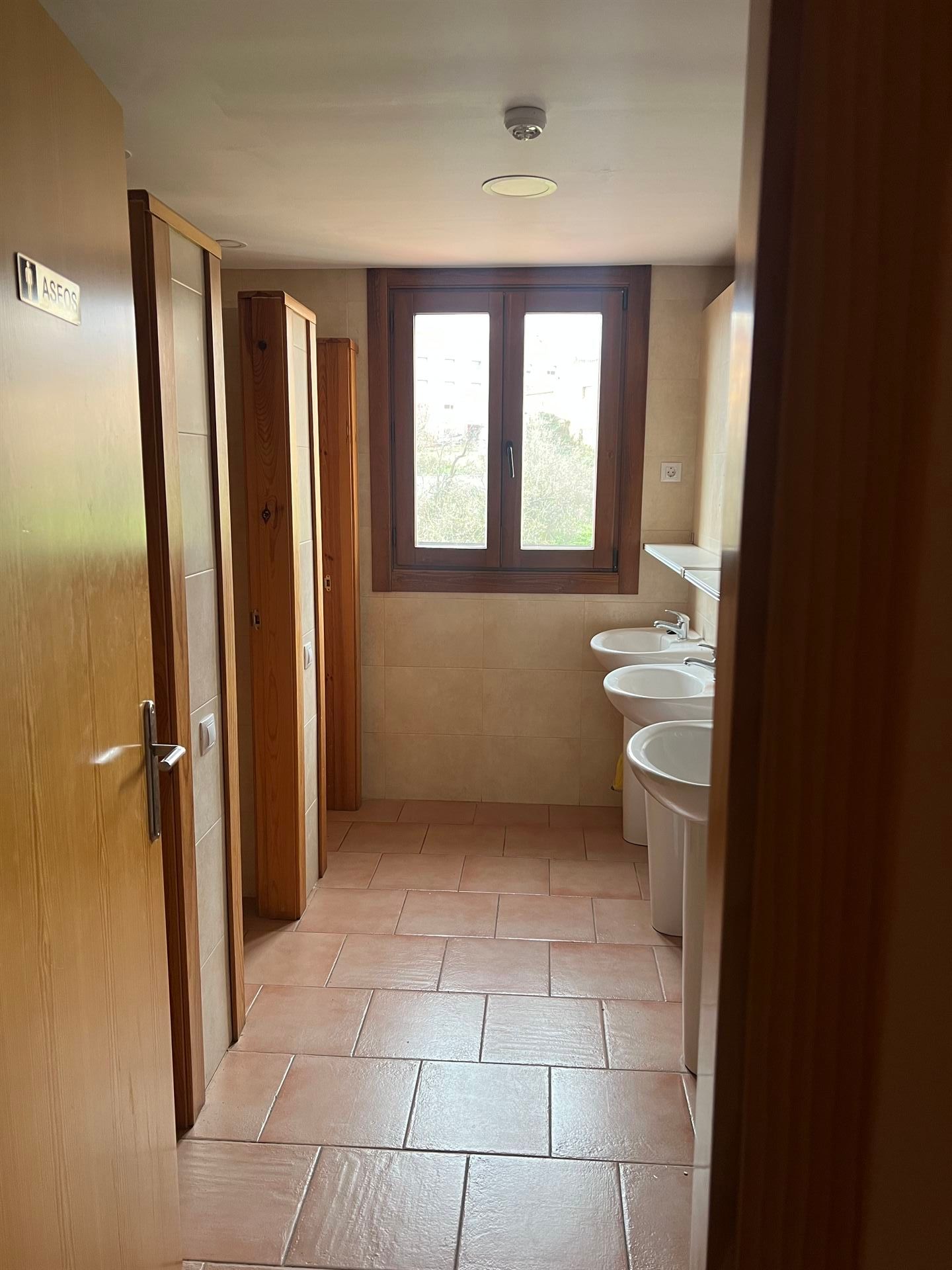 Un baño con muchos lavabos y una ventana.
