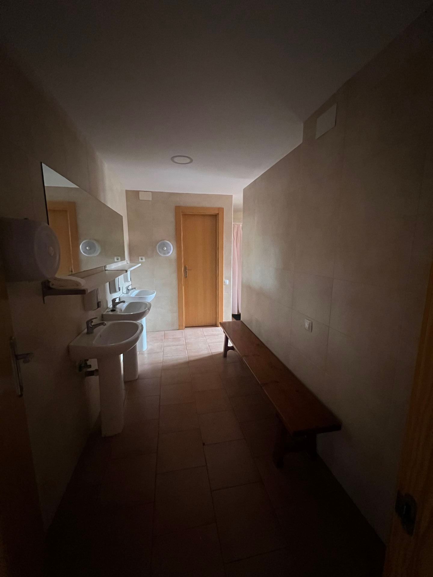 Un baño con lavabo, un banco y un espejo.