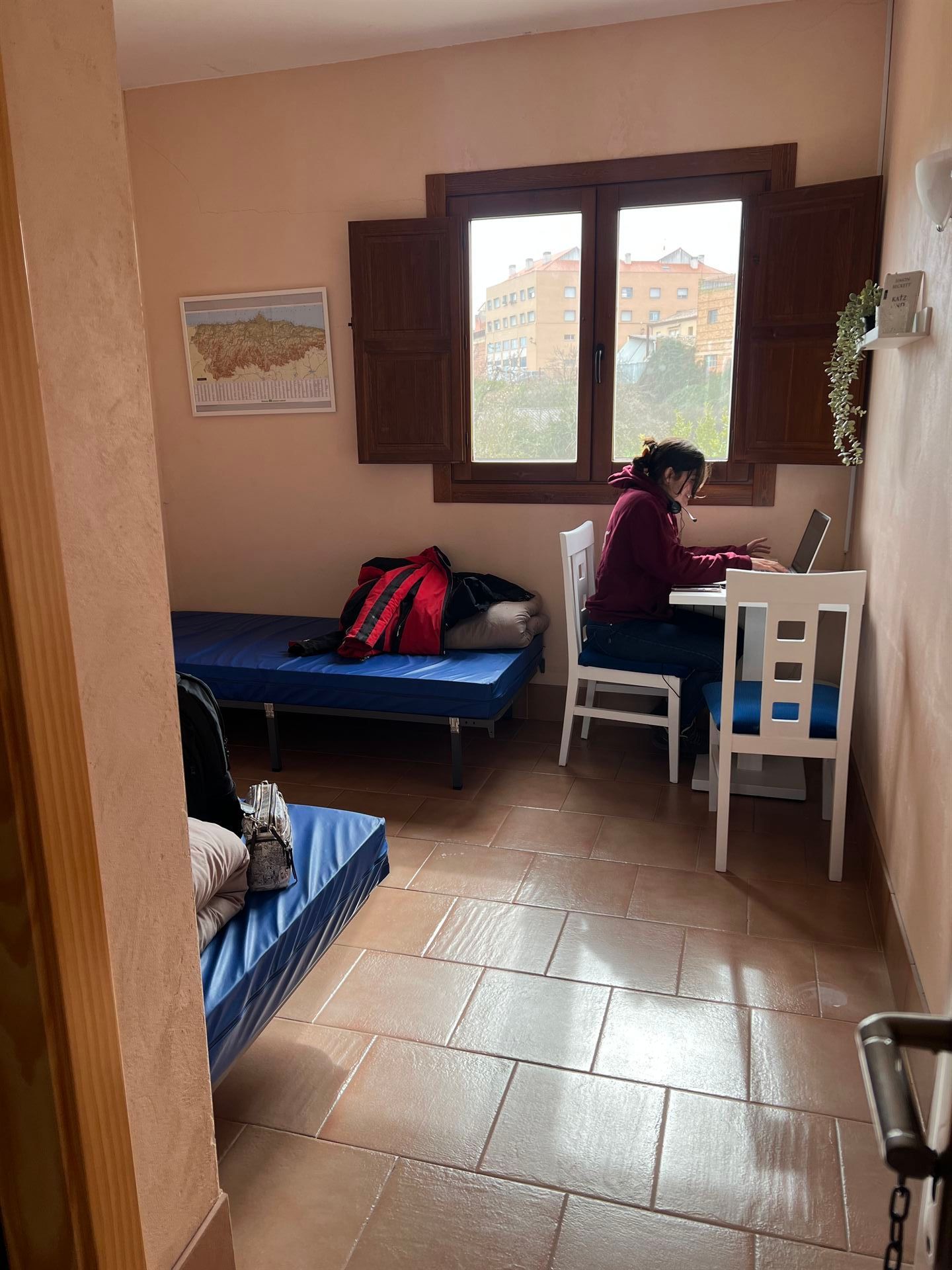 Una mujer está sentada en una mesa en una habitación con una computadora portátil.