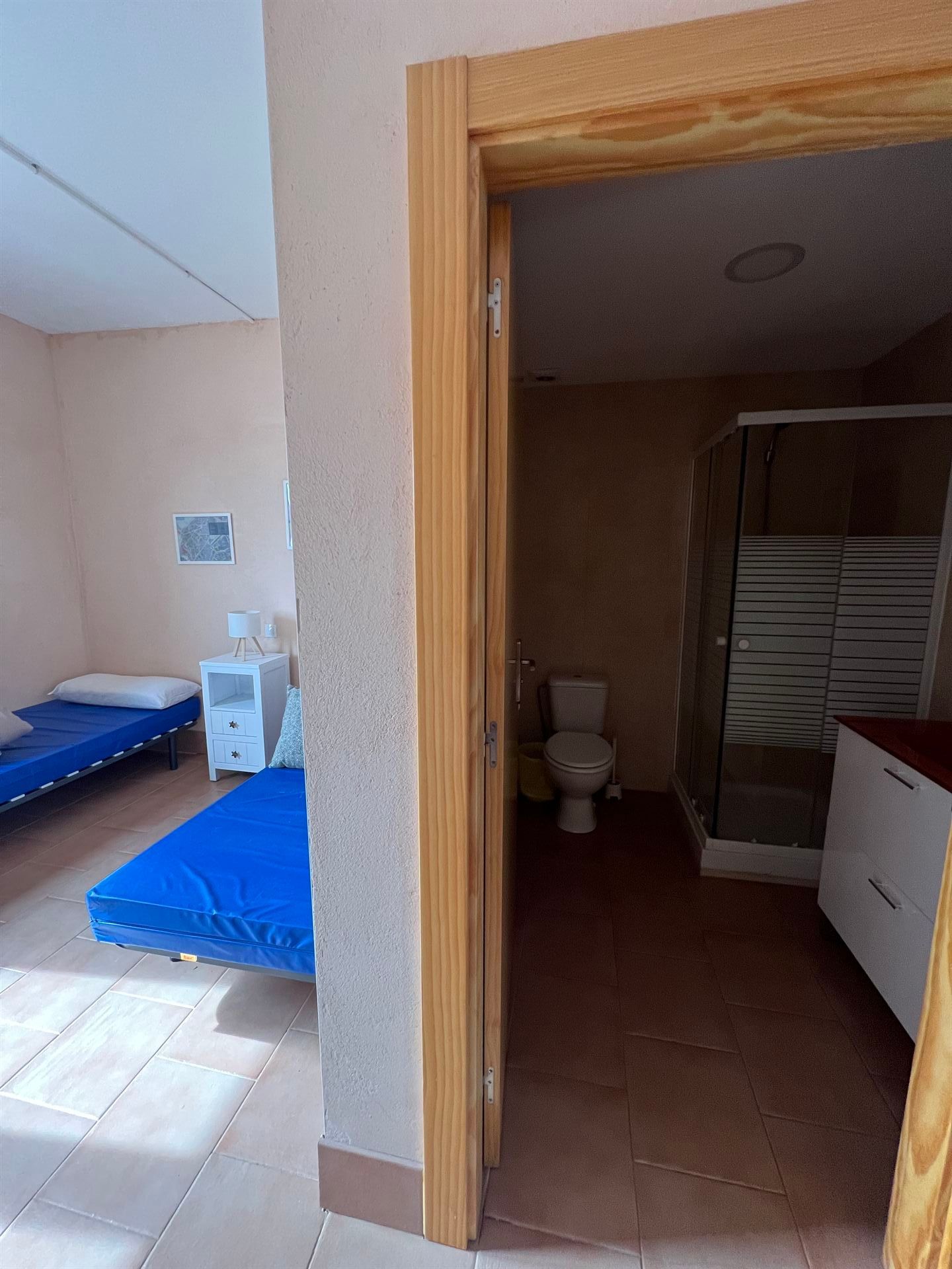 Un dormitorio con dos camas y un baño con WC.