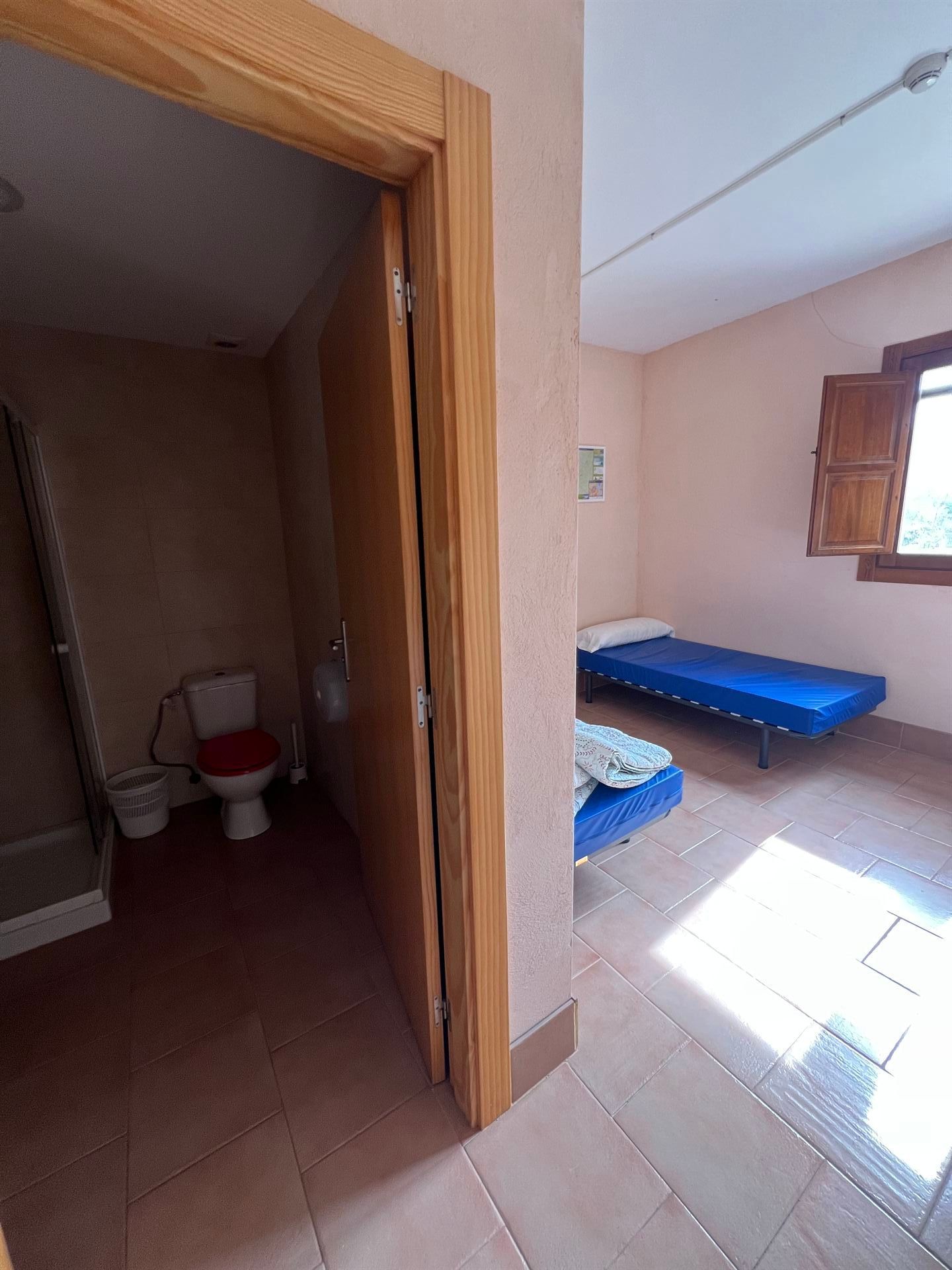 Un baño con inodoro y dos camas.
