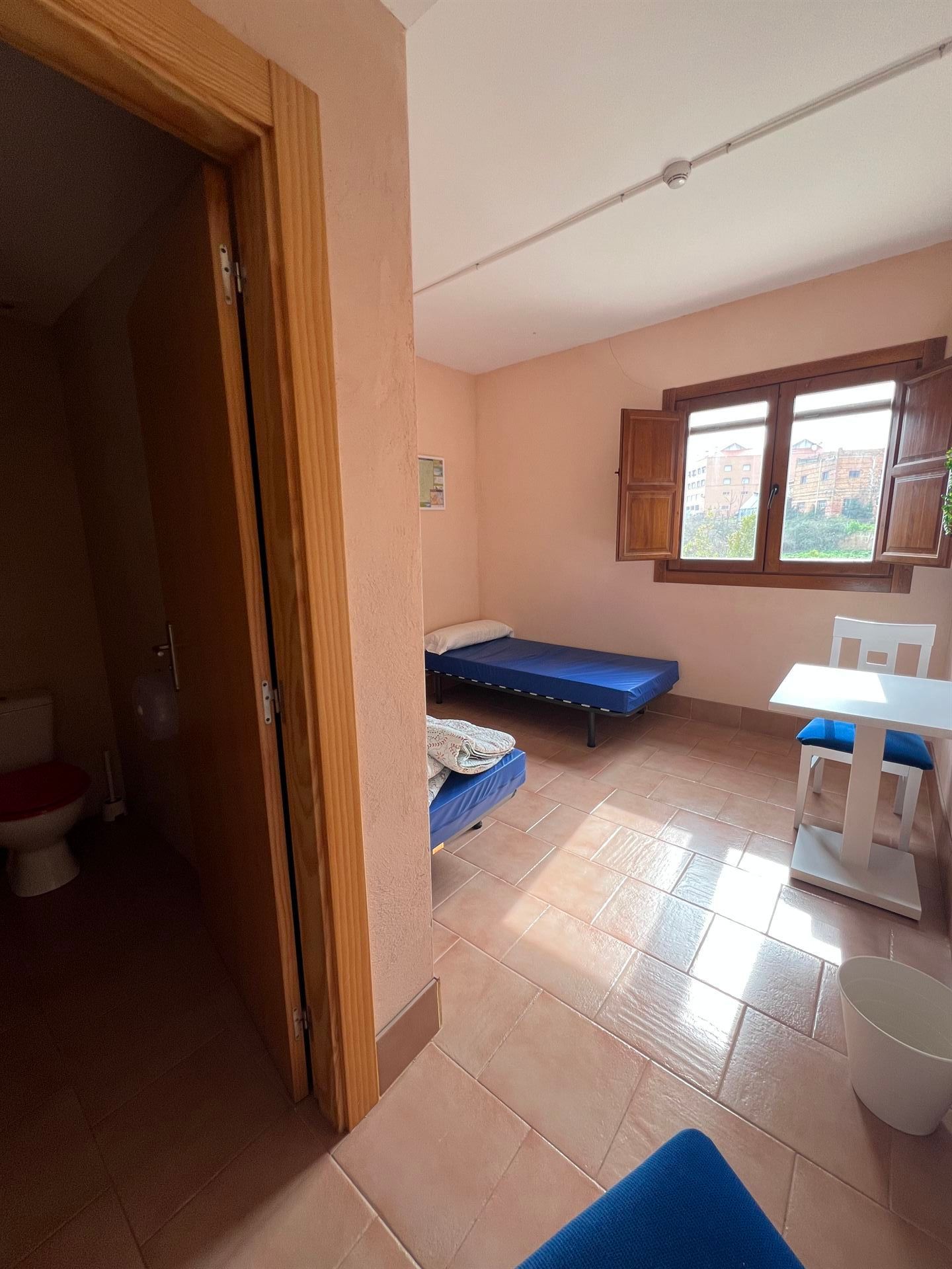 Una habitación con una cama, mesa, sillas y un baño
