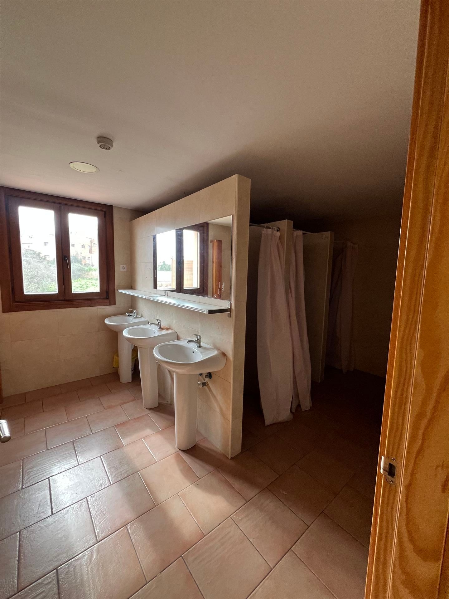Un baño con una fila de lavabos y una cabina de ducha.
