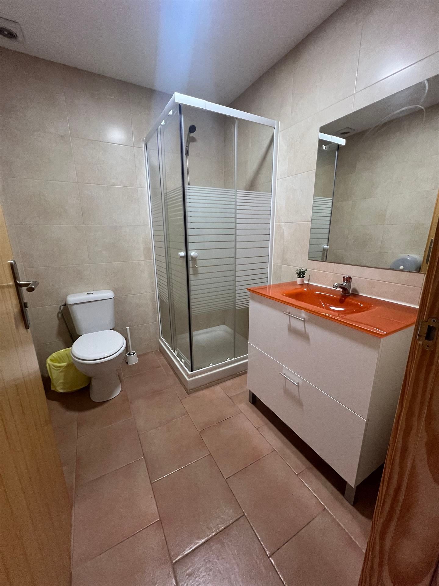 Un baño con inodoro, lavabo, ducha y espejo.