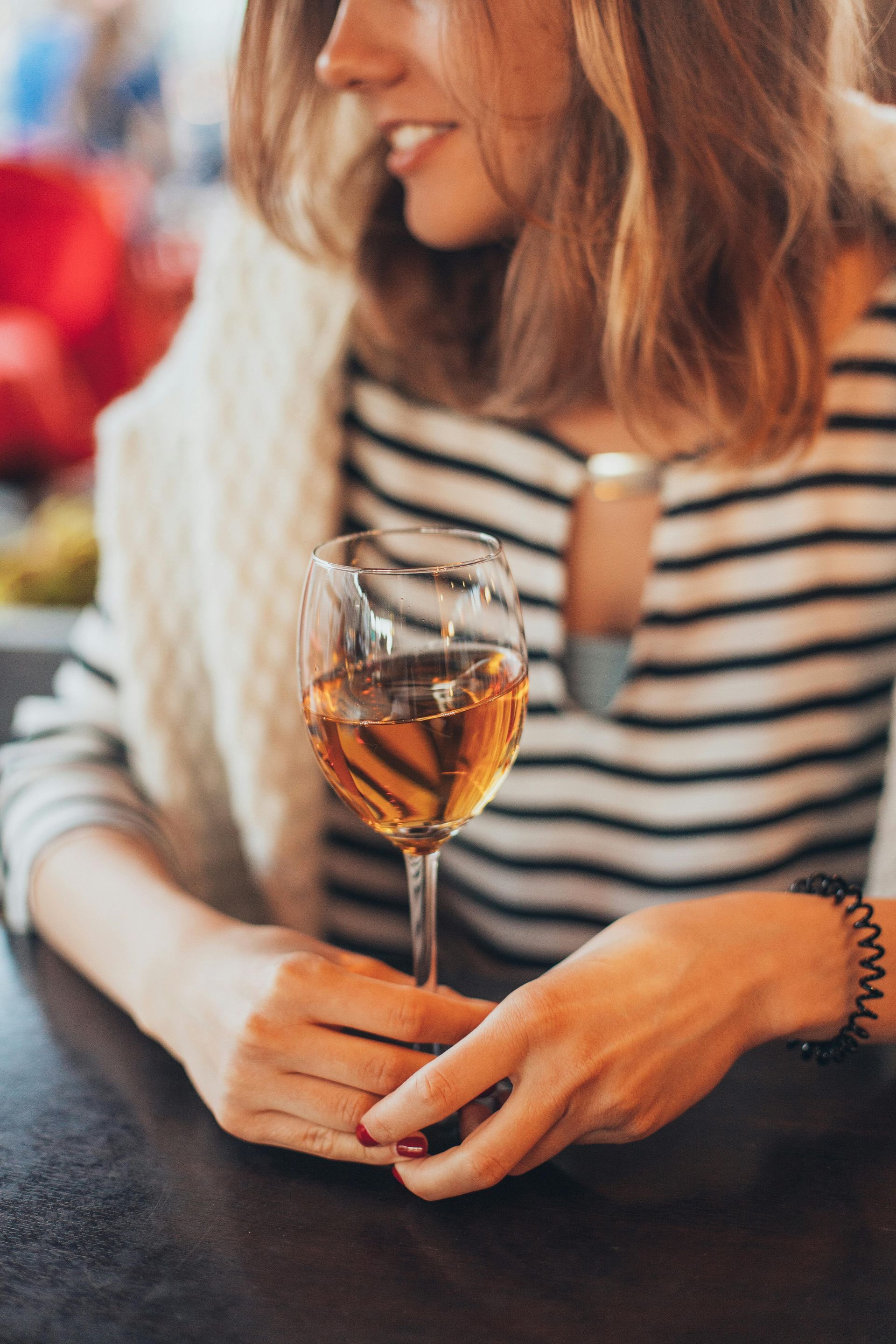 Una mujer está sentada en una mesa sosteniendo una copa de vino.