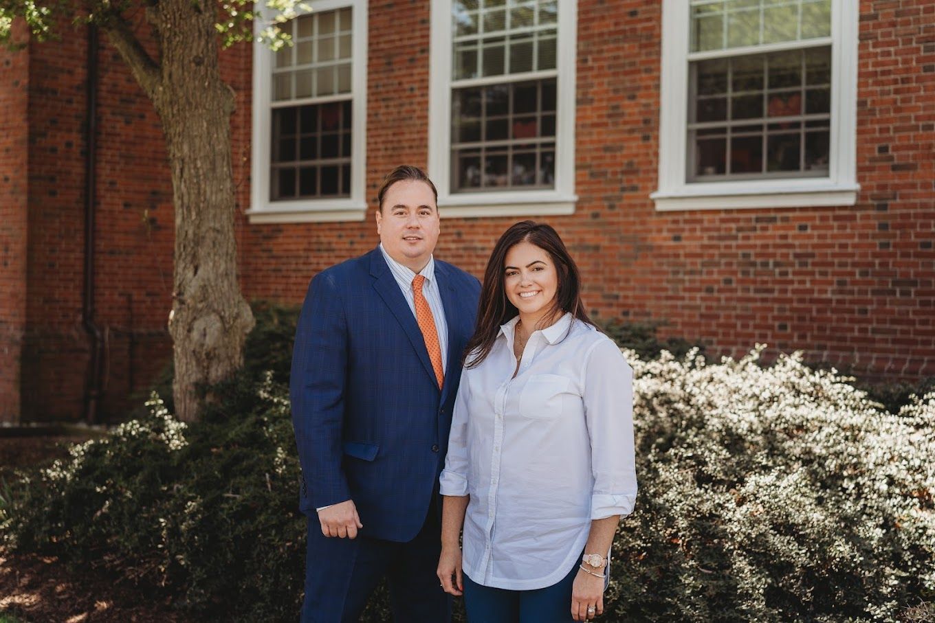 a man and a woman are standing in front of a brick building .