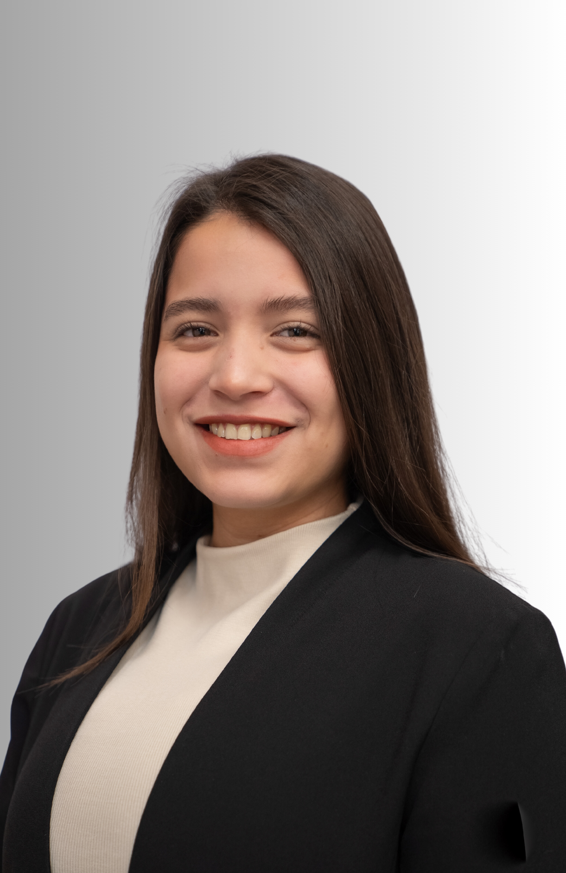 A woman in a black jacket and white sweater is smiling for the camera.