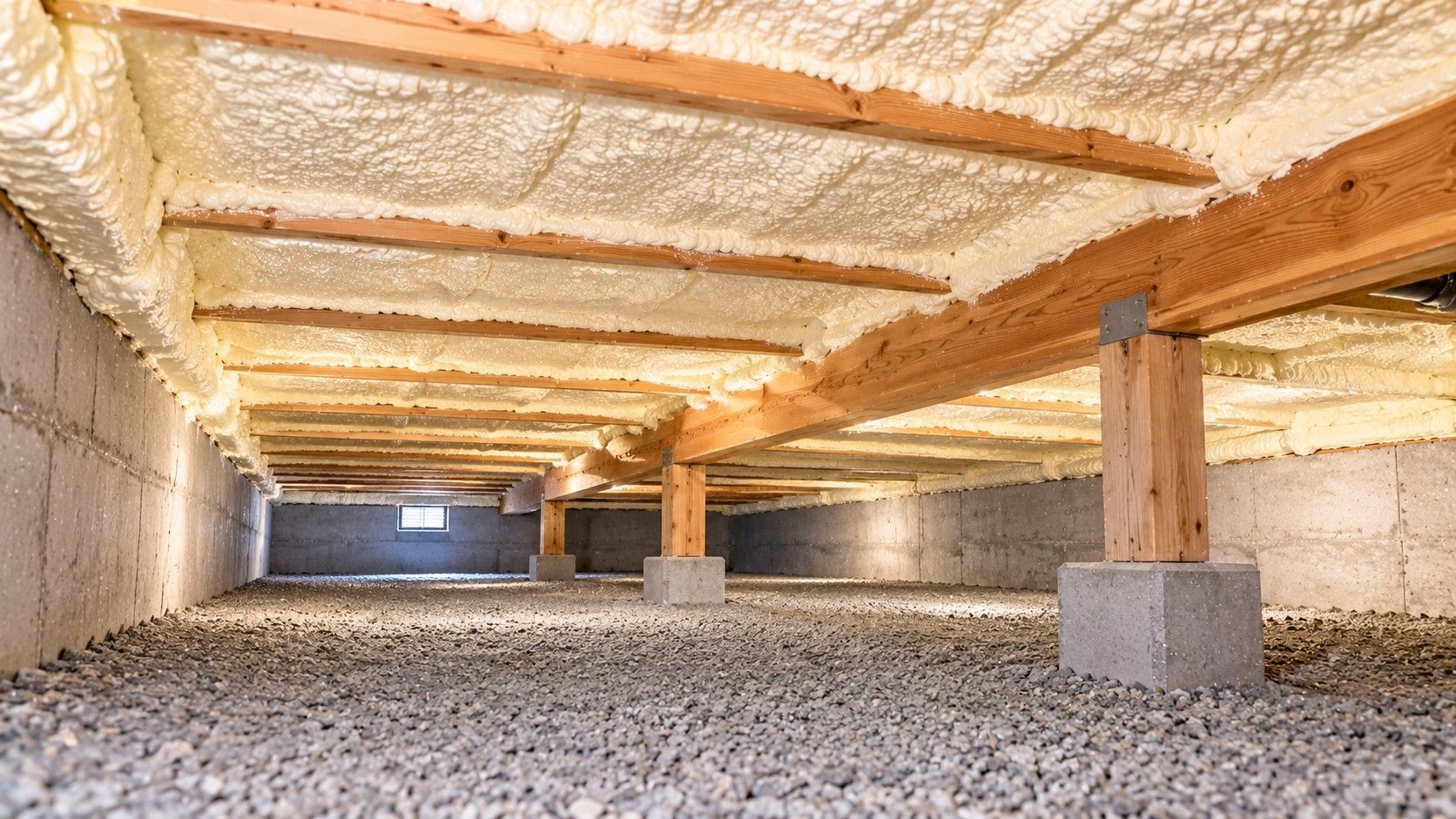 Completed crawl space spray foam insulation beneath a modern residential home with evenly insulated wooden floor joists.