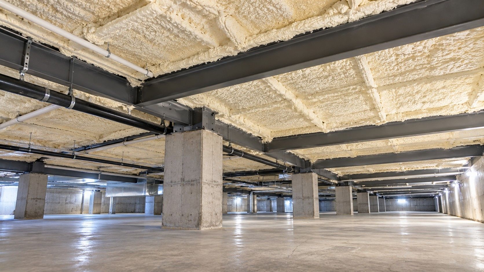 Completed commercial crawl space spray foam insulation with insulated steel framing, concrete support piers, and clean flooring.