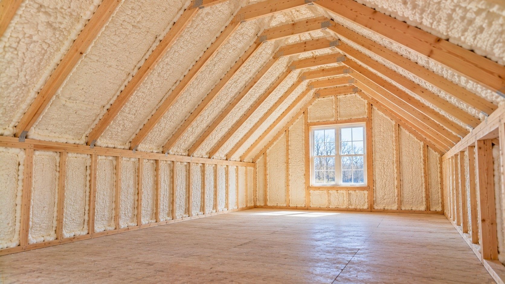 Completed open-cell spray foam insulation along sloped ceilings and knee walls inside a residential bonus room above a garage.