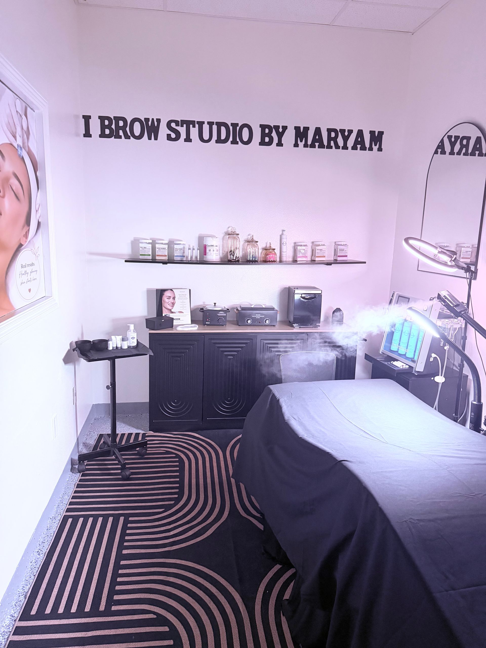Eyebrow studio with a treatment bed, shelves, mirror, and black-and-white patterned rug