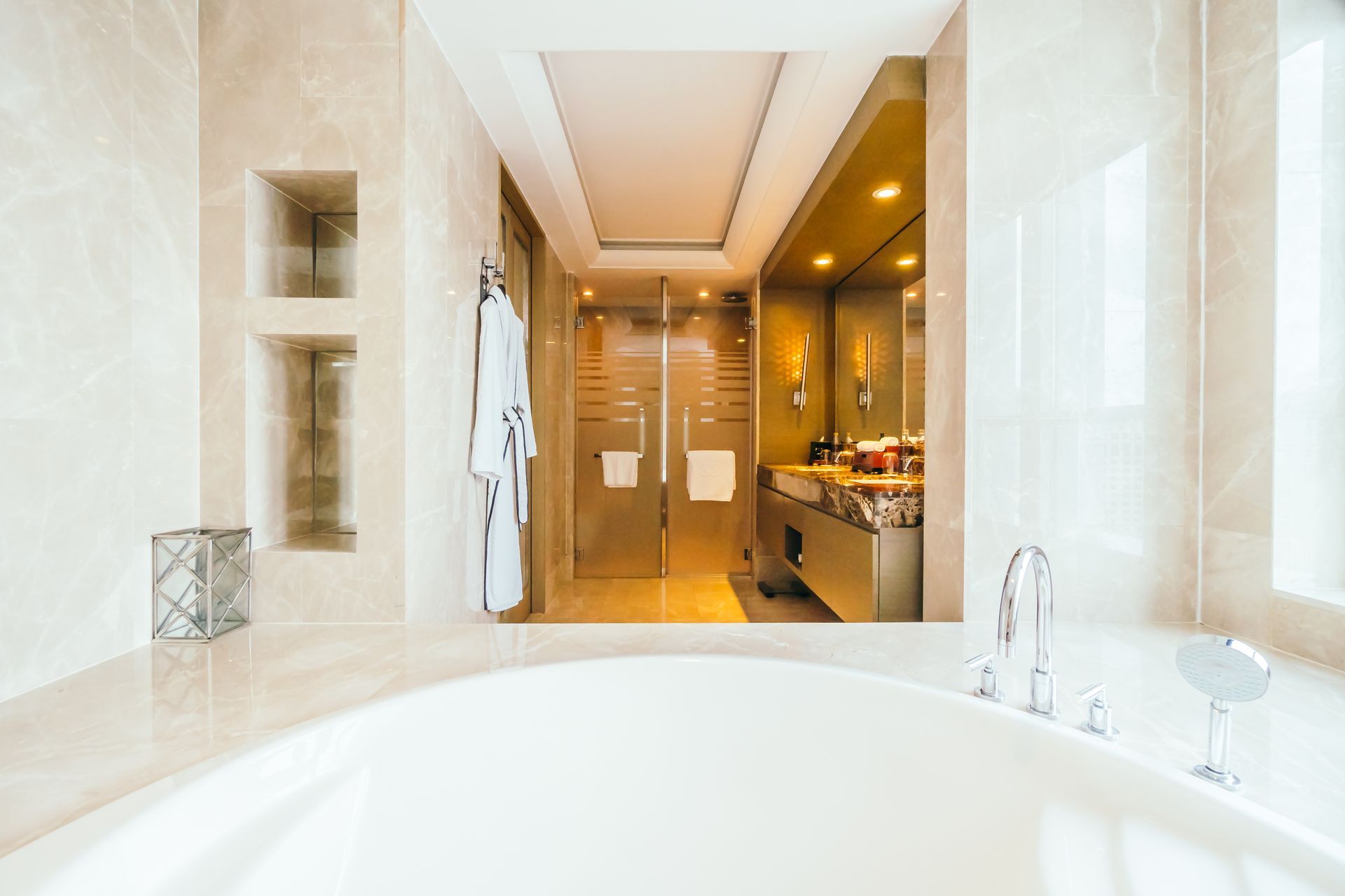 Bright luxury bathroom with a large tub, glass shower, and double sink vanity under warm lighting
