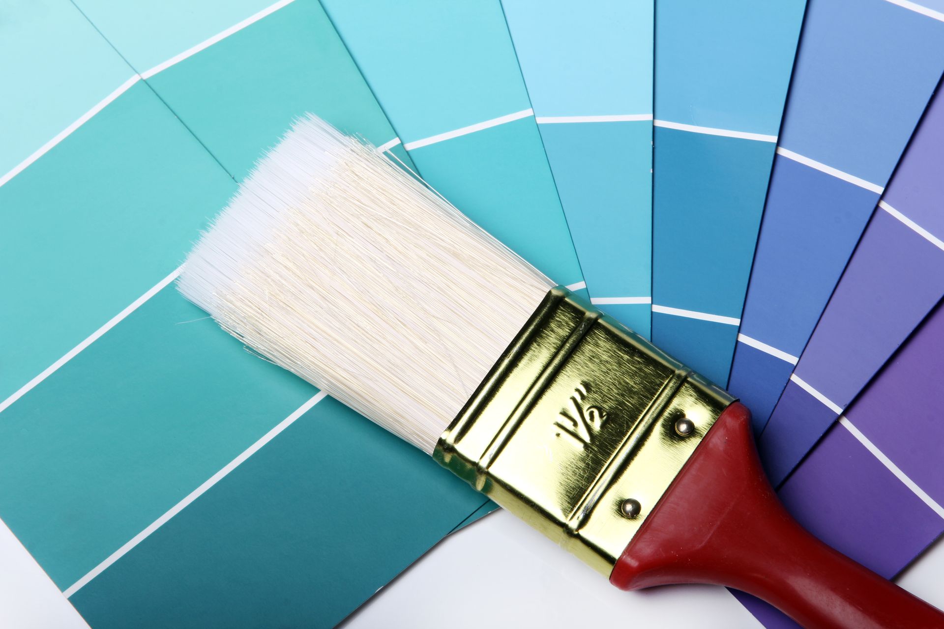 A paint brush is sitting on top of a fan of blue and purple paint samples