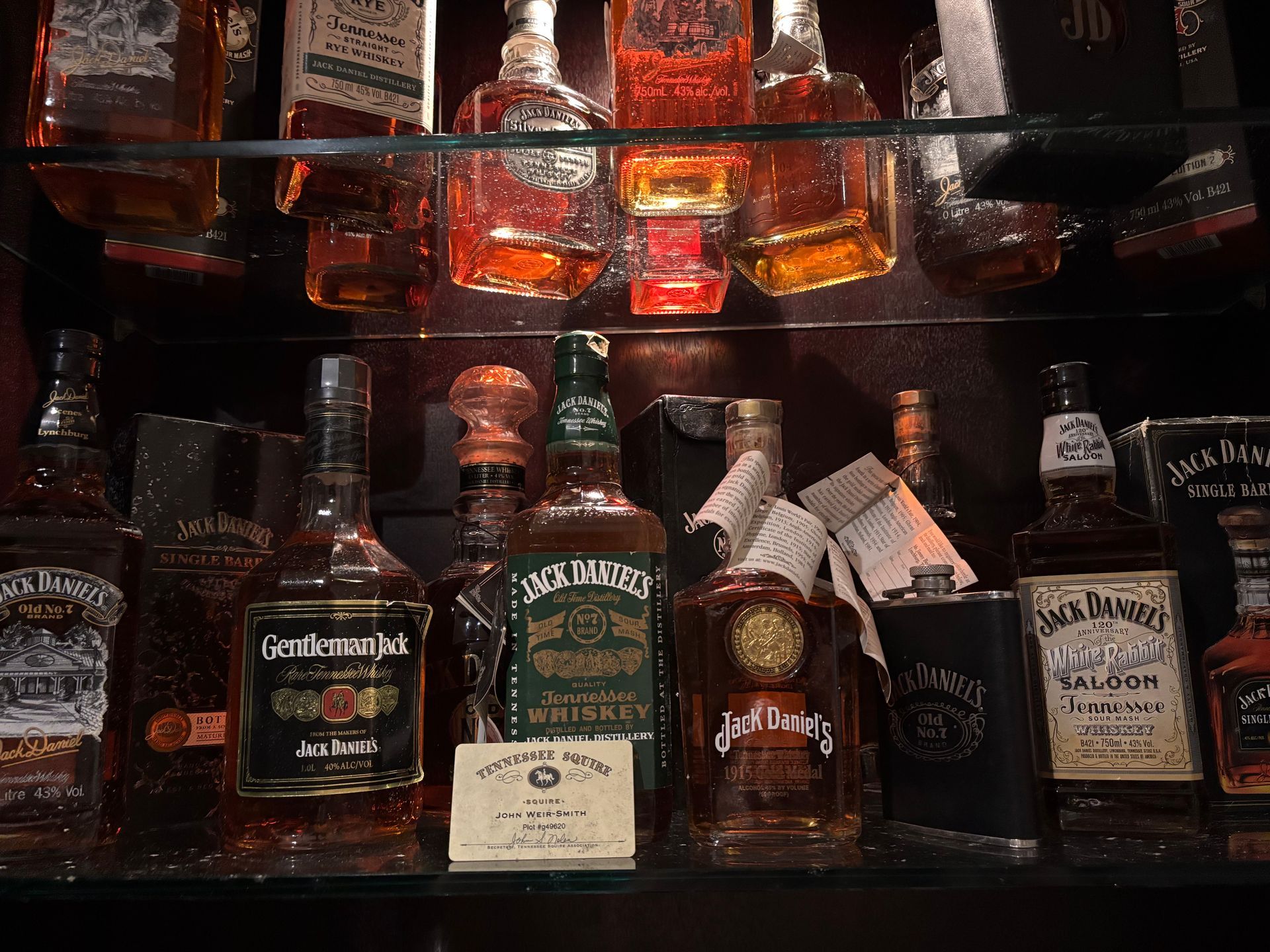 Two shelves filled with various bottles of Jack Daniel’s Tennessee whiskey arranged against a dark background.