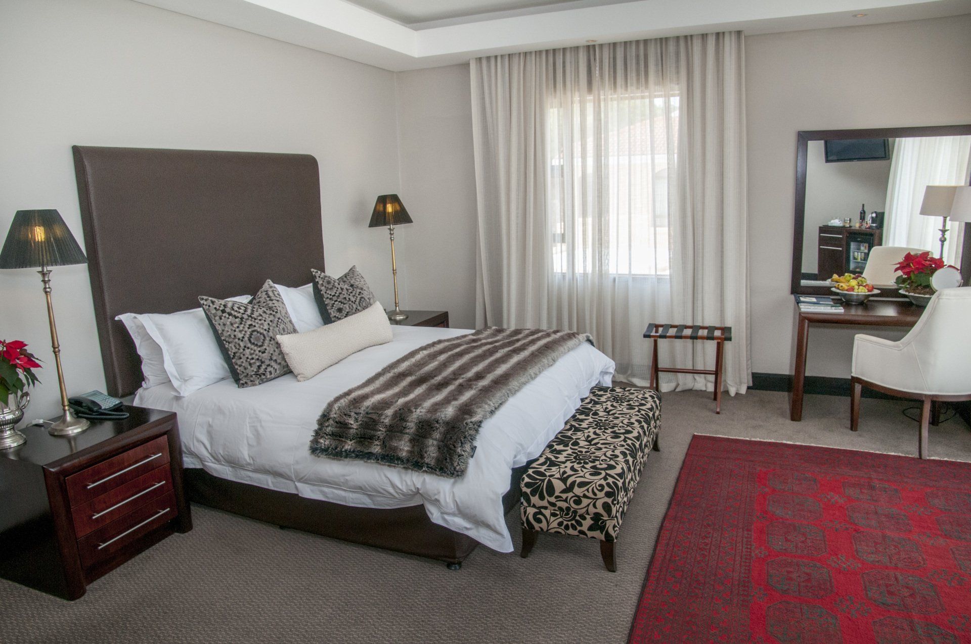 Hotel bedroom with a bed, desk, and rug.