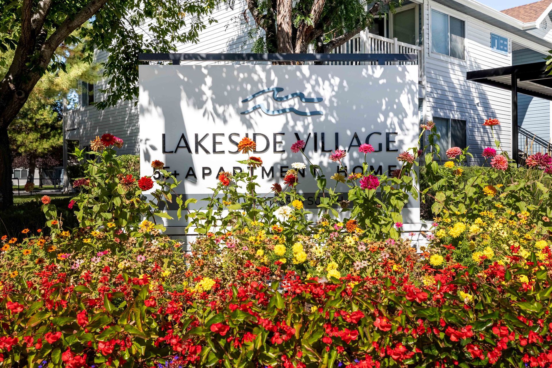 Sign for Lakeside Village Apartments, with floral garden in foreground.