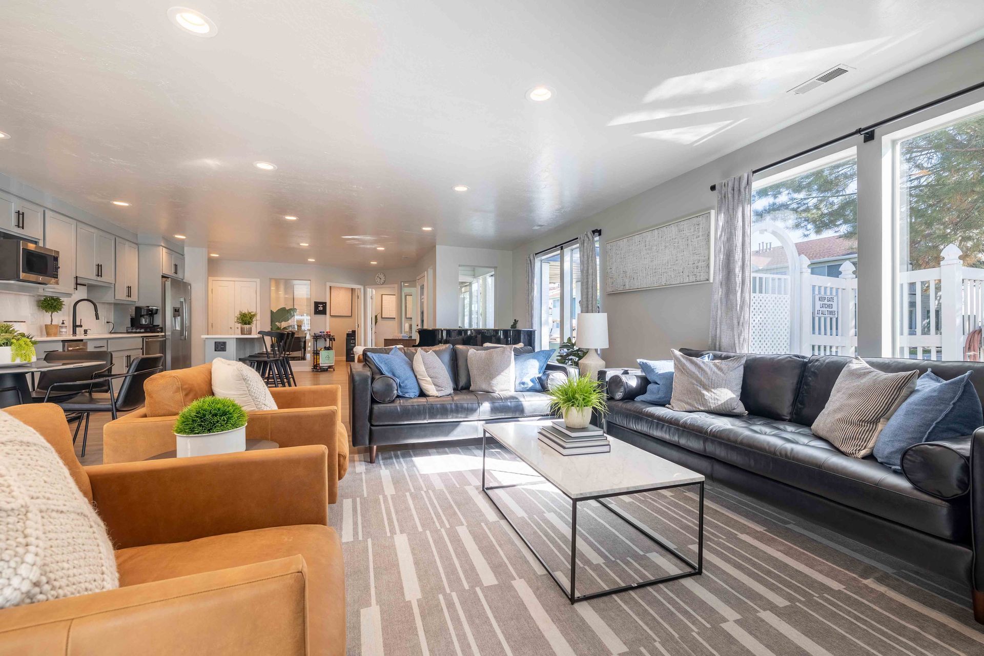 Spacious modern living room with gray sofas, brown chairs, and large windows.