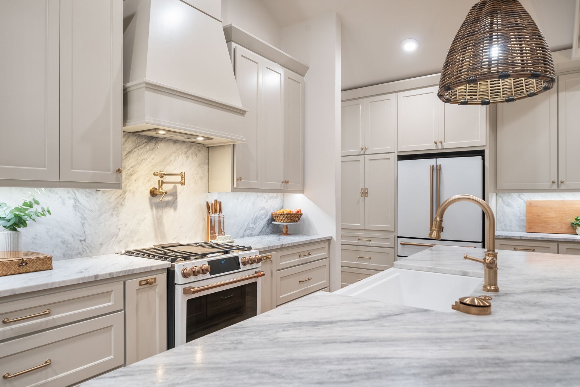 Modern kitchen with white cabinetry, a dark island, stainless steel appliances, and light wood flooring.