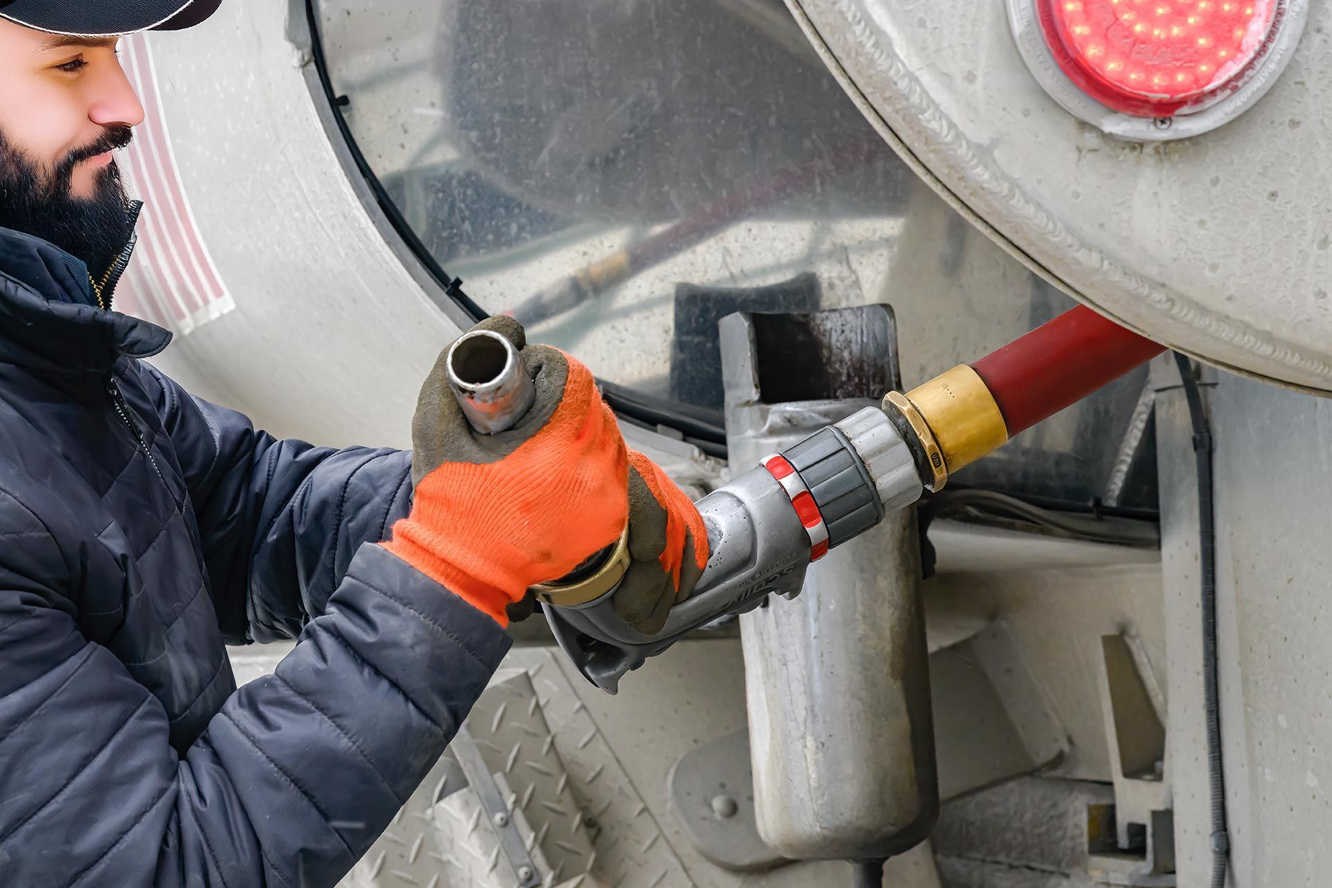 A driver operating a truck pulls out a hose to begin heating oil delivery. A driver operating a truck pulls out a hose to begin heating oil delivery.
