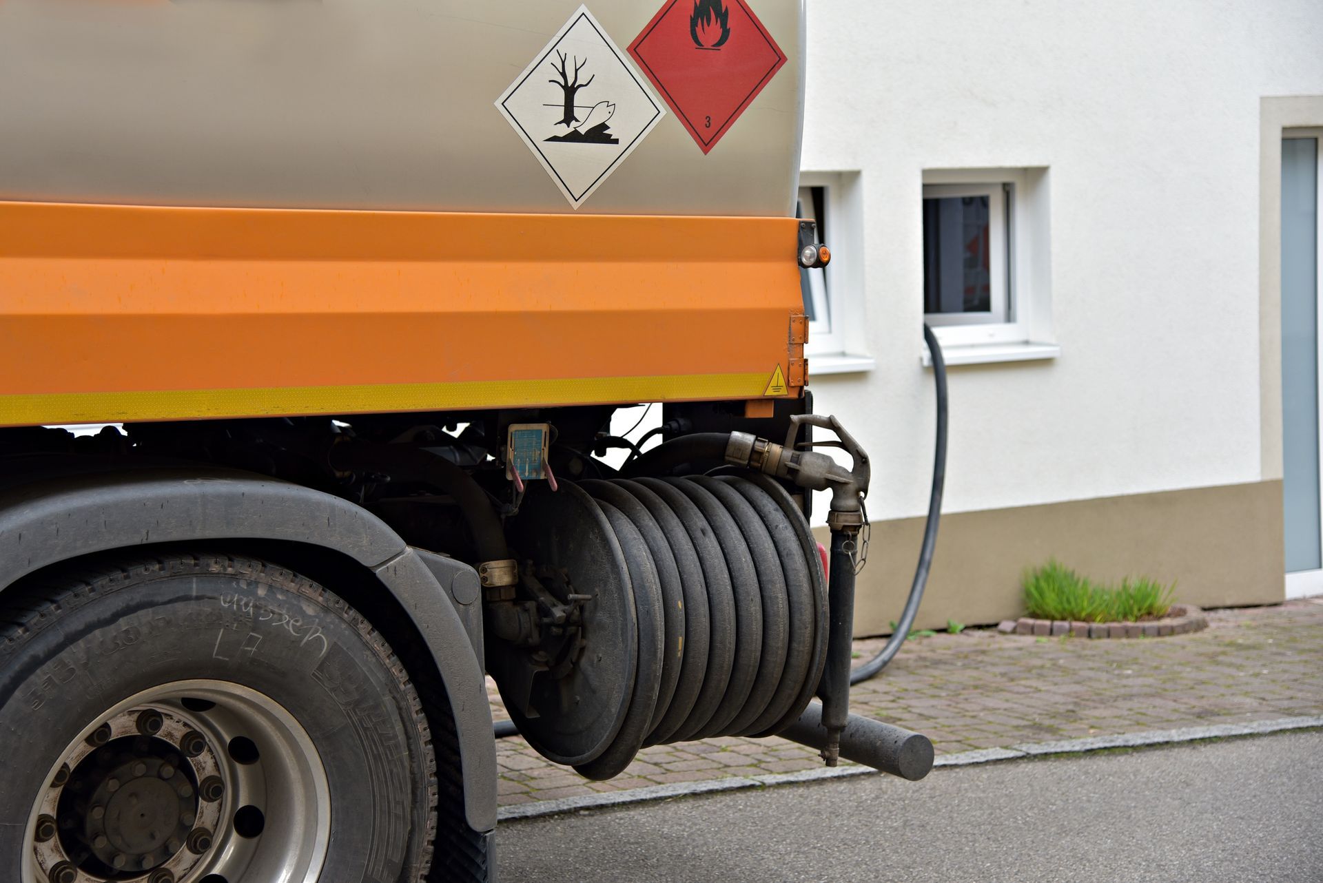 Oil truck parked near home delivering hesidential home heating oil with hose connection. Oil truck parked near home delivering hesidential home heating oil with hose connection.