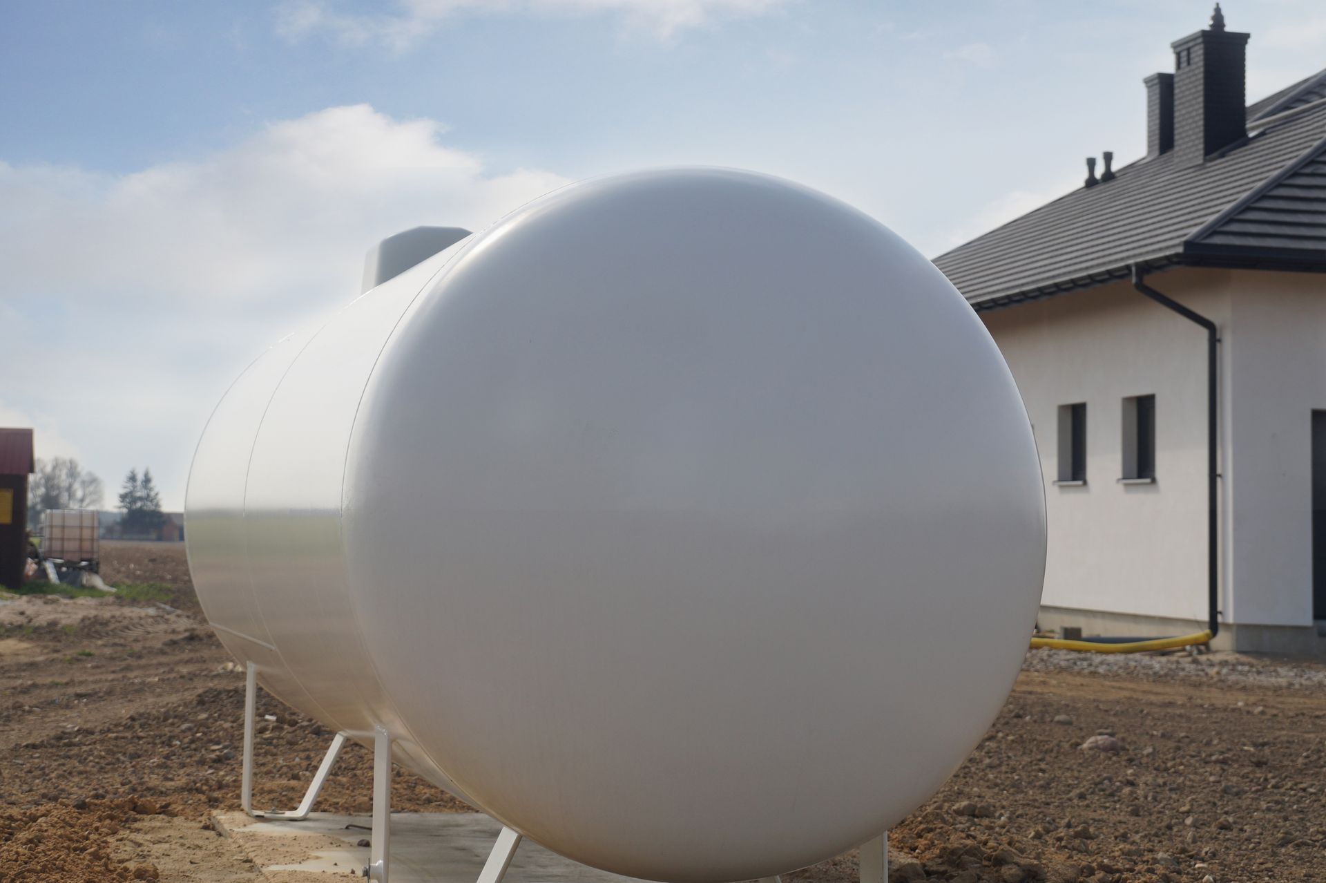 Residential home heating oil tank installed beside modern house in outdoor residential yard area. Residential home heating oil tank installed beside modern house in outdoor residential yard area.