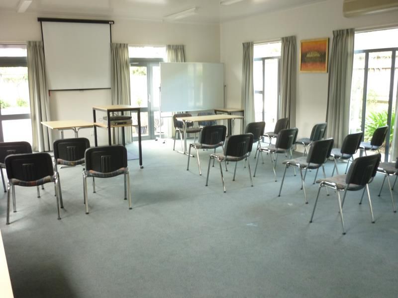 A room with tables and chairs and a projector screen