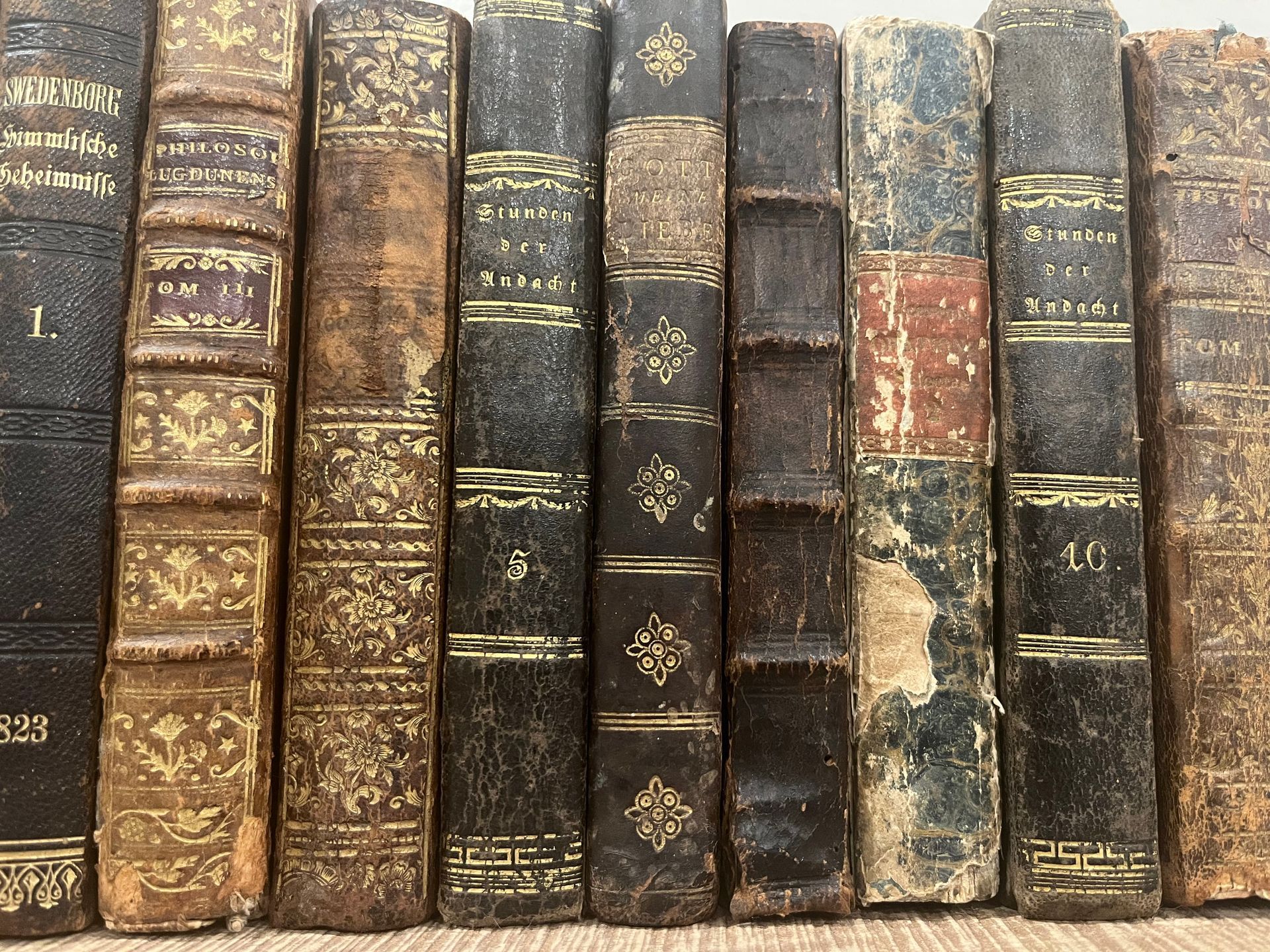 Row of worn antique leather-bound books with faded gold lettering on their spines