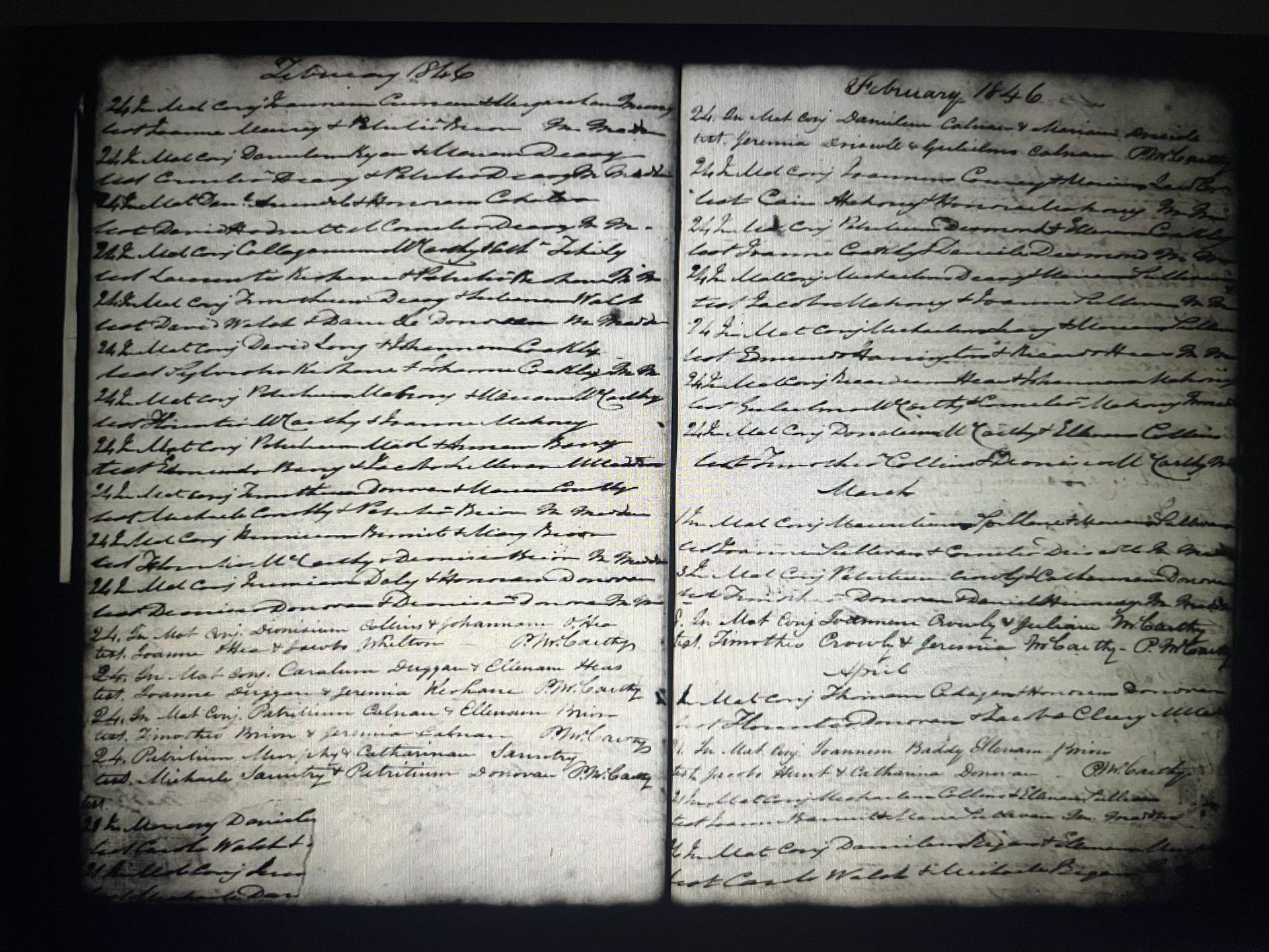 Open manuscript spread with handwritten cursive on two aged pages, lit against a dark background