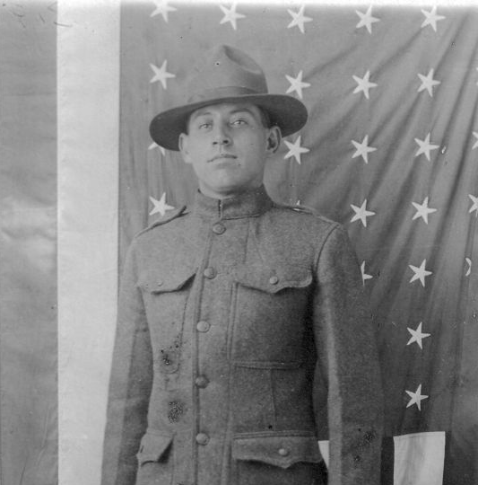 Man in military uniform and hat standing before a star-patterned backdrop