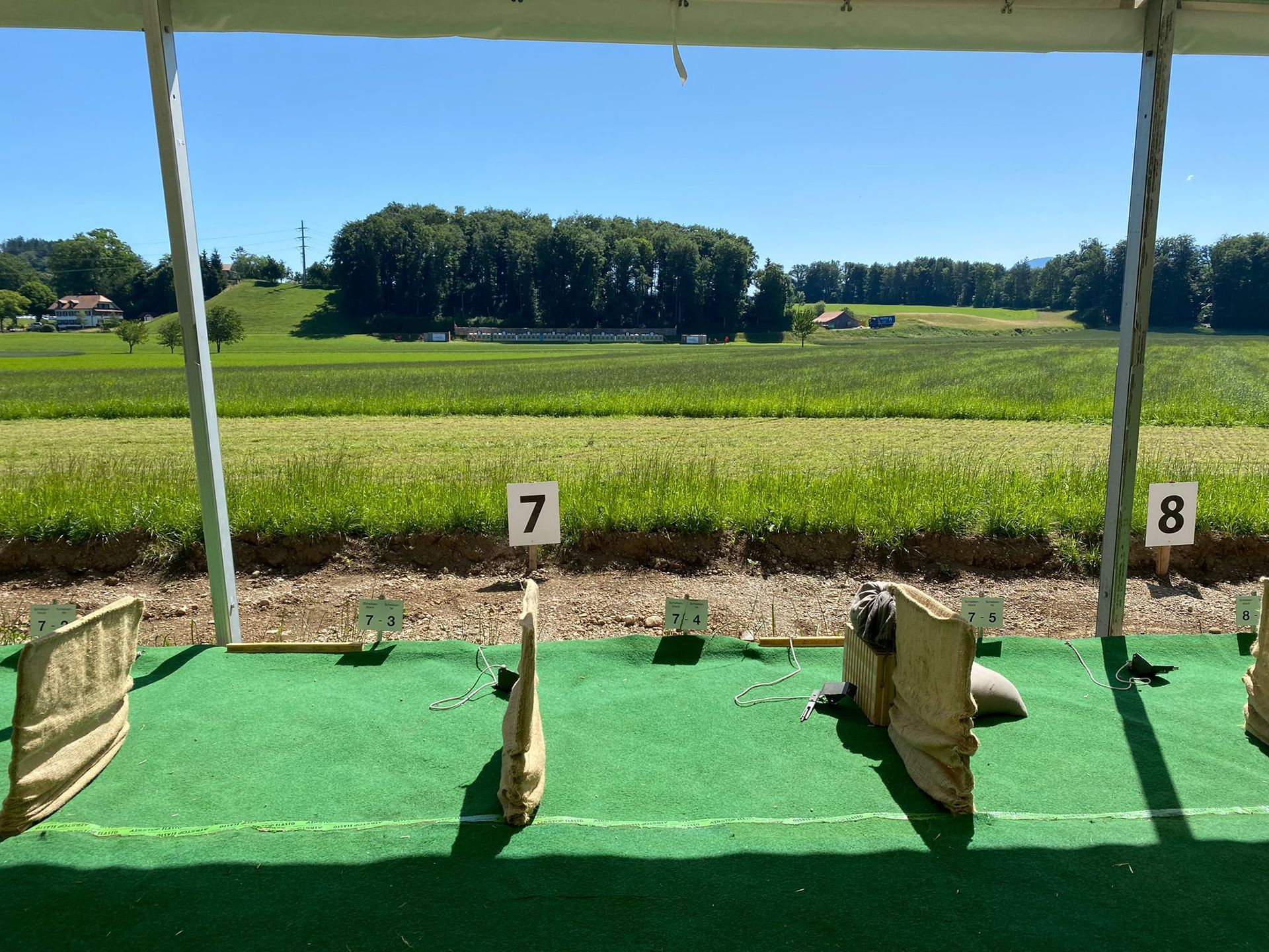 Shooting range lanes 7 and 8 with targets under a canopy, overlooking a grassy field and trees