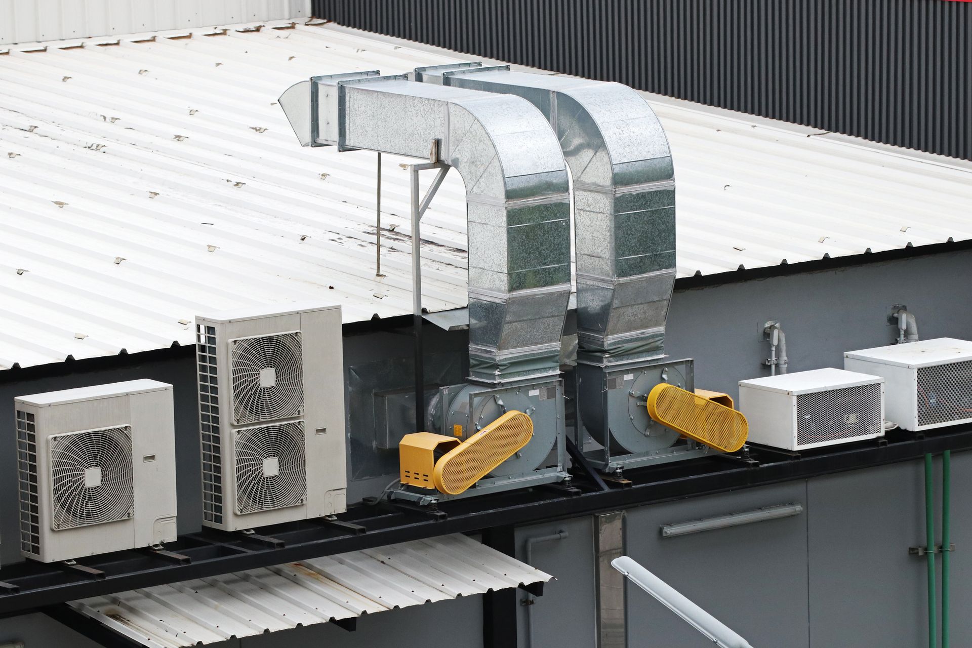 HVAC units on a building roof, with metallic ductwork and exhaust fans.