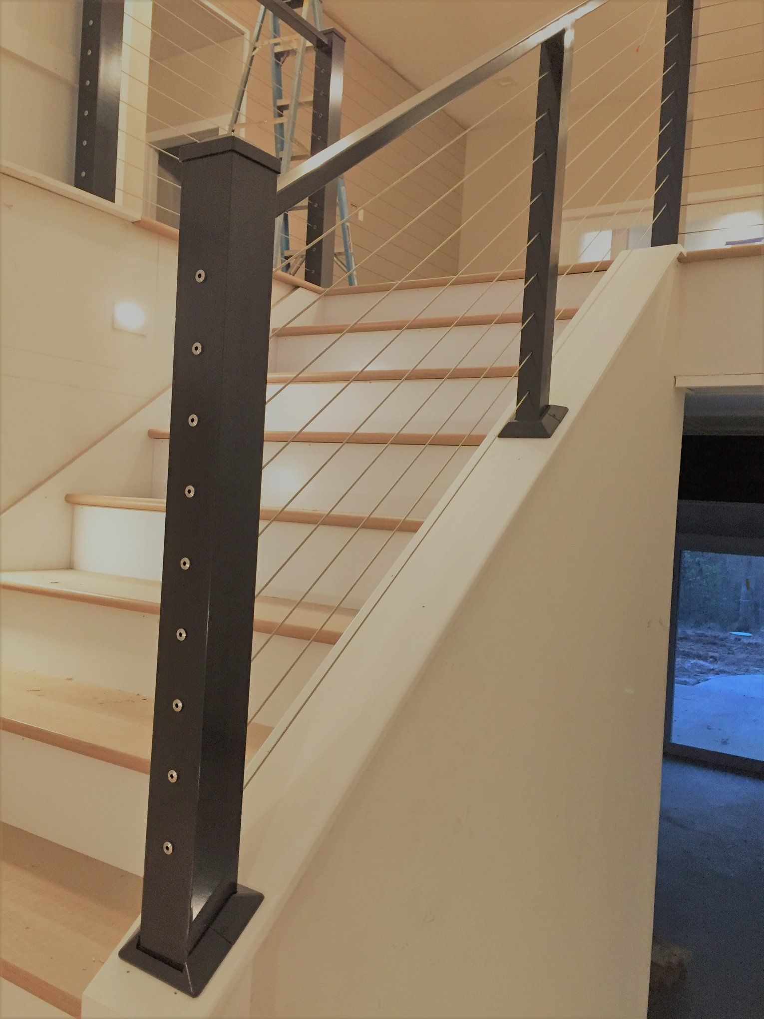 Indoor staircase with black metal railing and beige walls, viewed from the side.