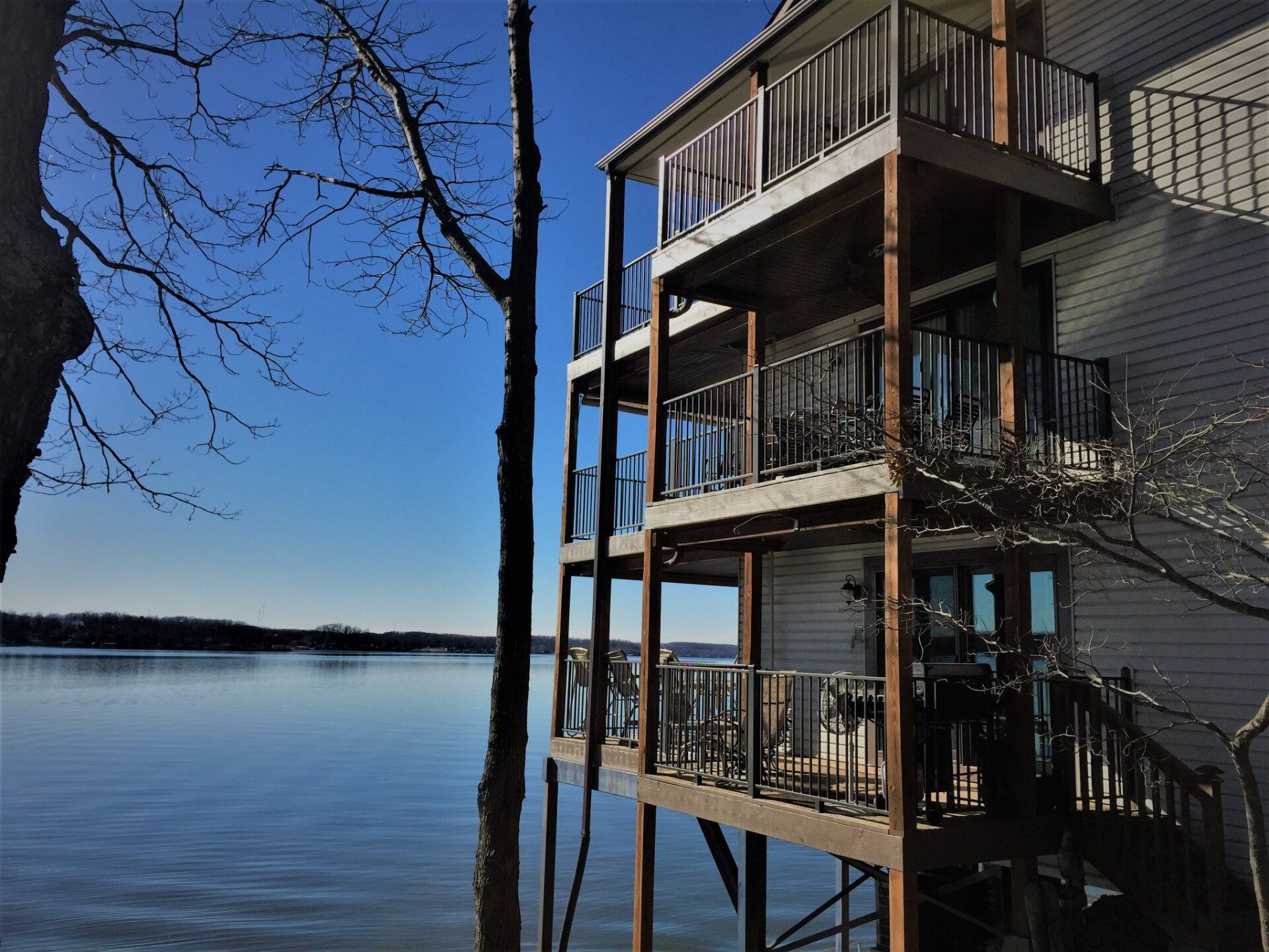 Lakefront condo deck beside a calm blue lake under a clear sky