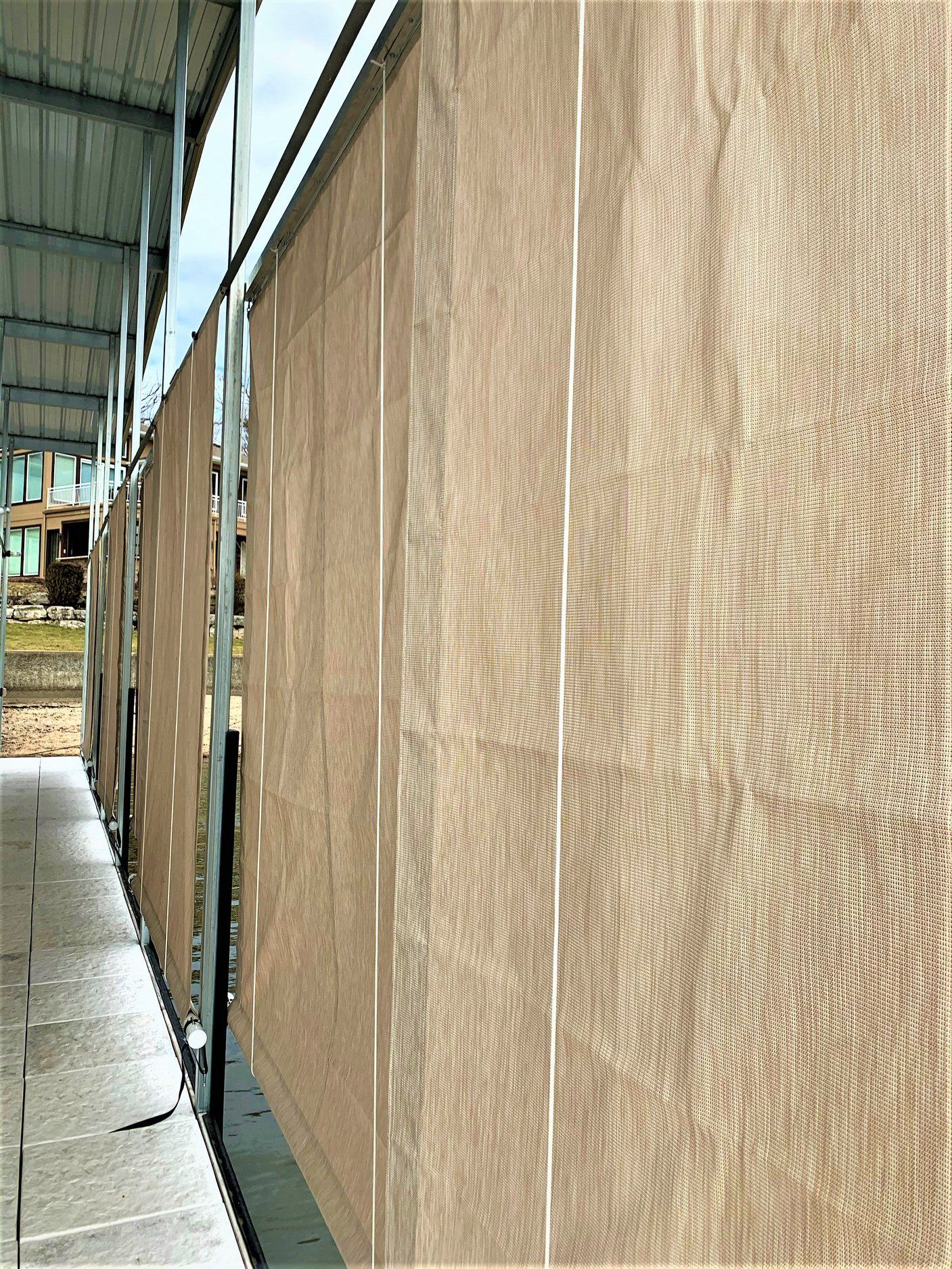 Temporary tan wood-panel construction wall along a walkway beside a building