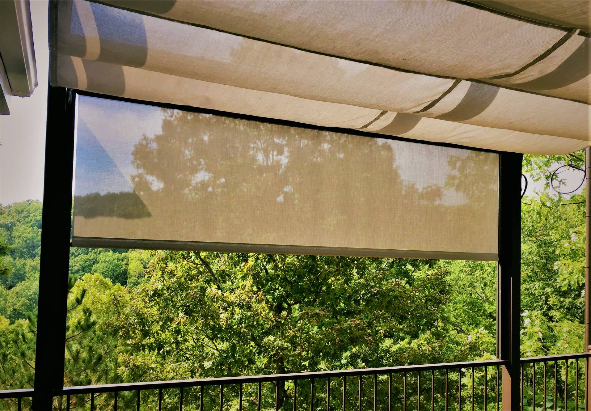 Outdoor patio with a beige retractable sun shade partially lowered over a green treetop view