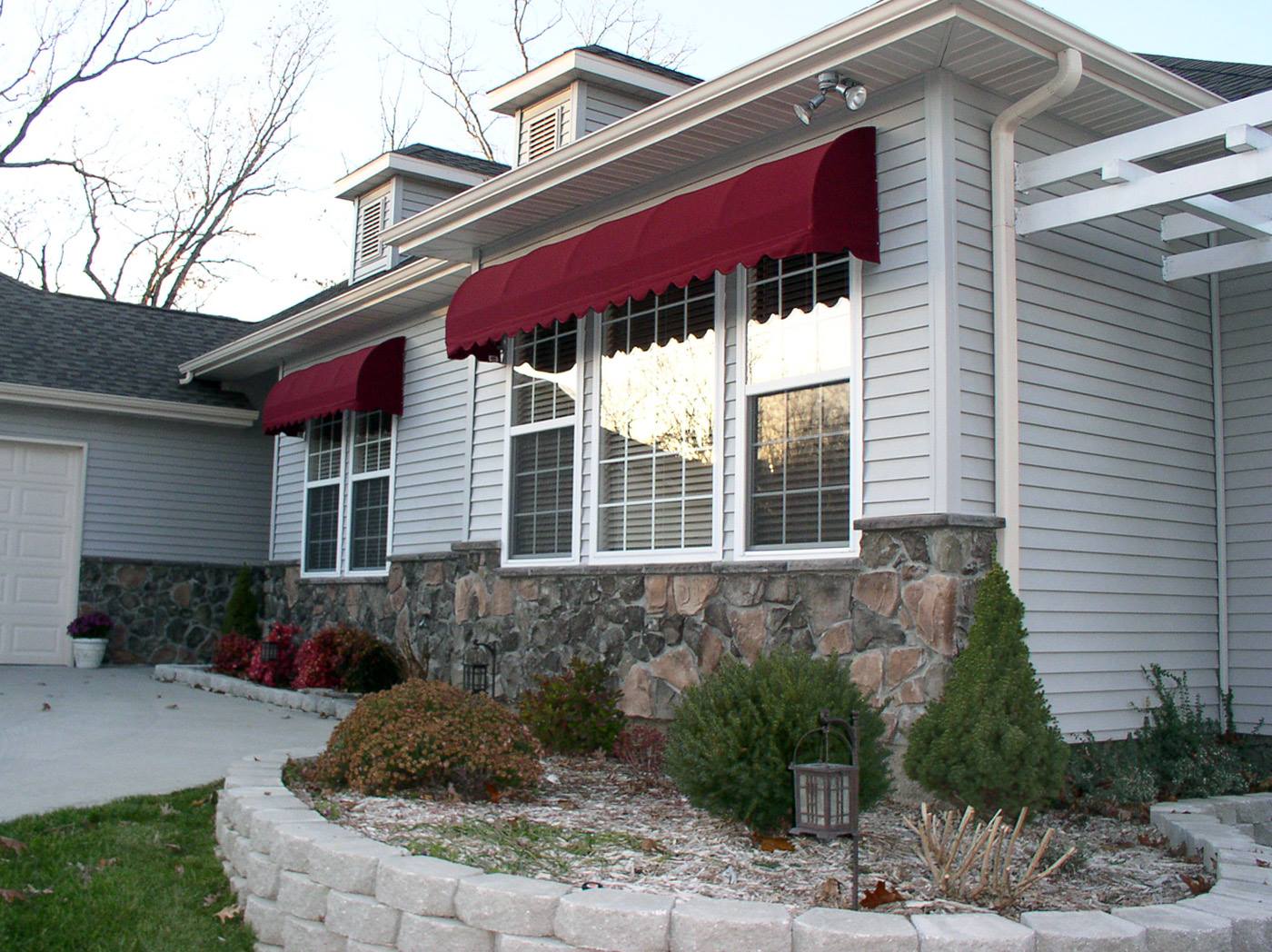 House exterior with red awnings, stone facade, and a landscaped front entry